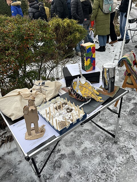 Auf einem Tisch sind verschiedene Modelle von Schülern zu sehen, die Ideen für neue Gedenkzeichen im Außenraum der Gedenkstätte Poppenbüttel darstellen sollen. 